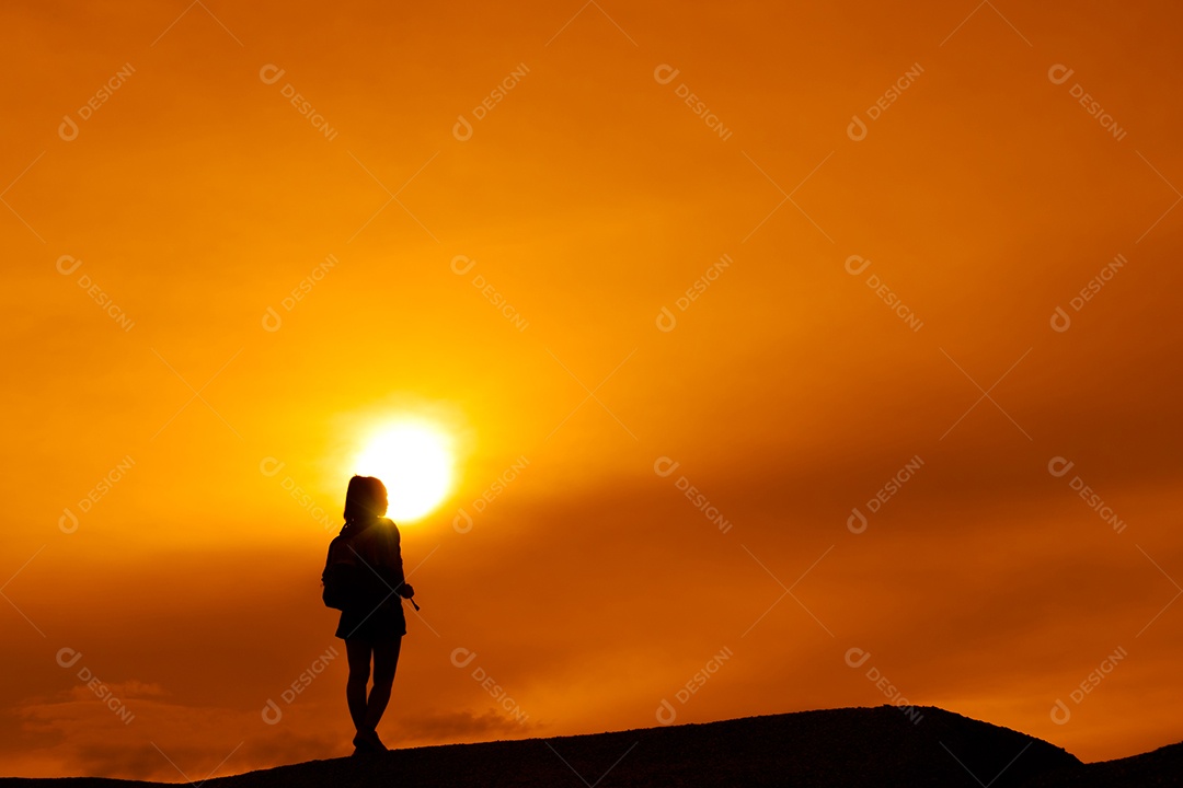 Menina asiática de mochila termina destinos na montanha olhando a silhueta do pôr do sol