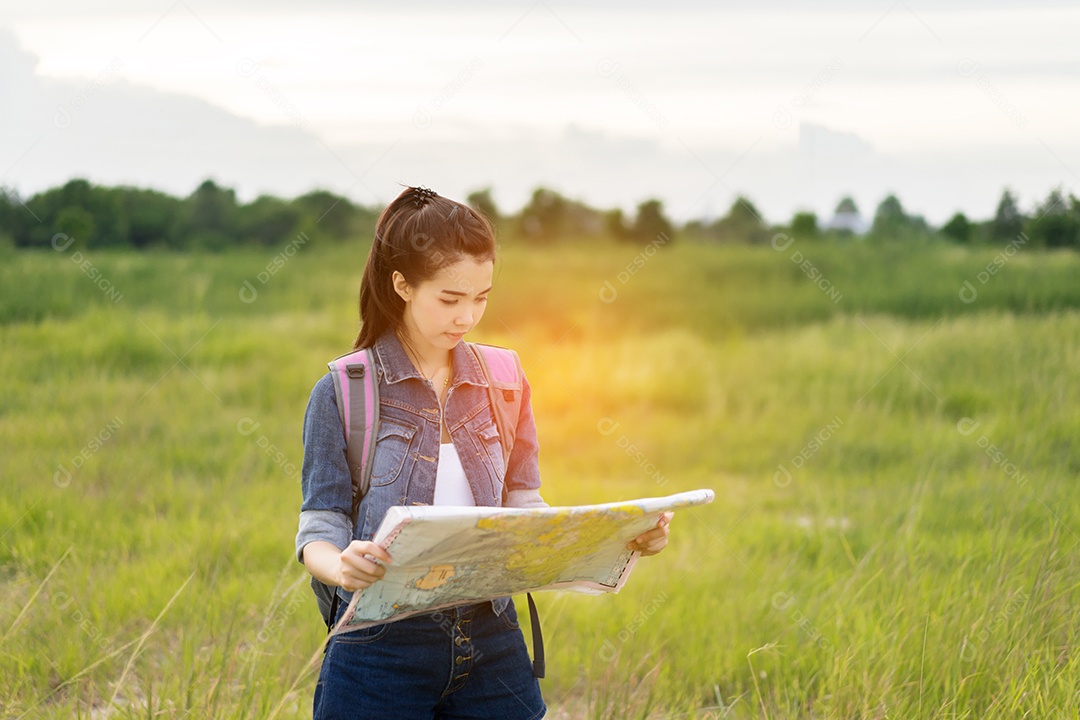 Menina asiática com mochila, mapas abertos, localização viagem na floresta