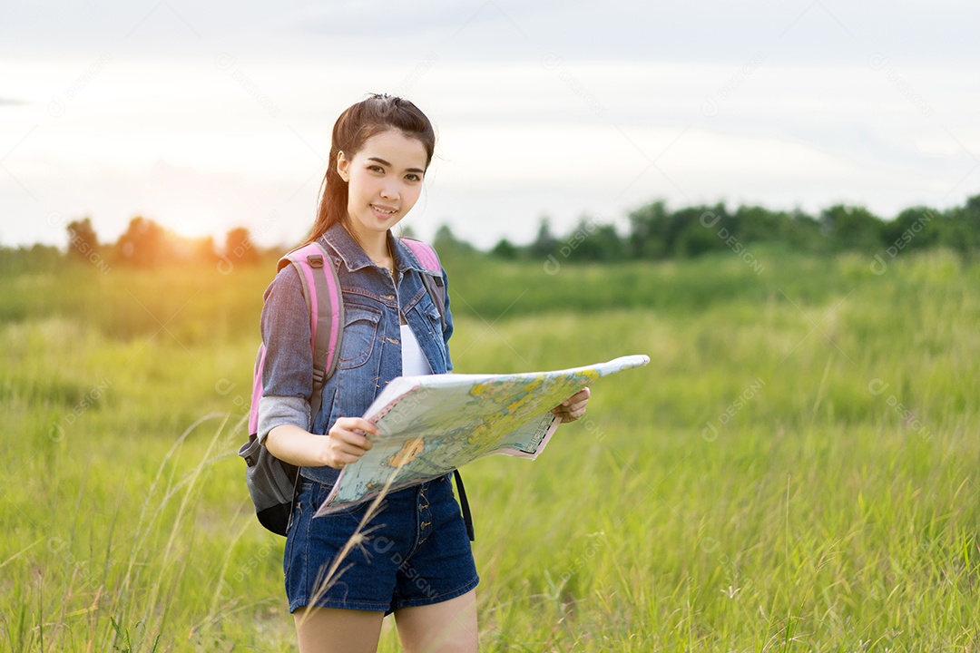 Menina asiática com mochila, mapas abertos, localização viagem na floresta
