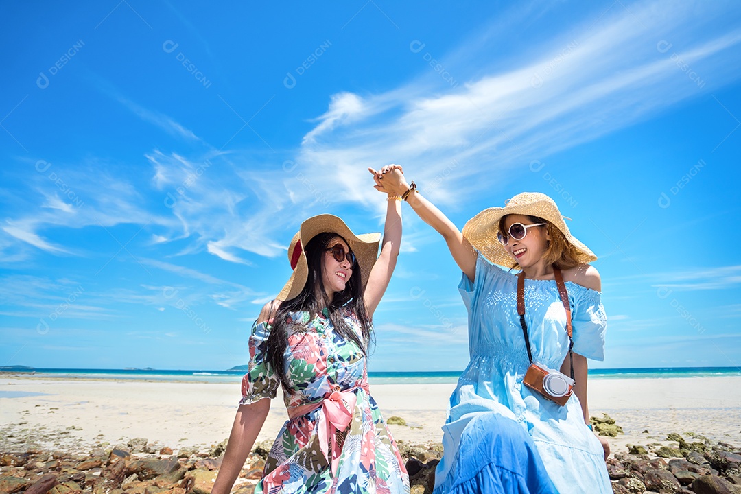 Jovens de vestido e chapéu na praia em tempo de férias