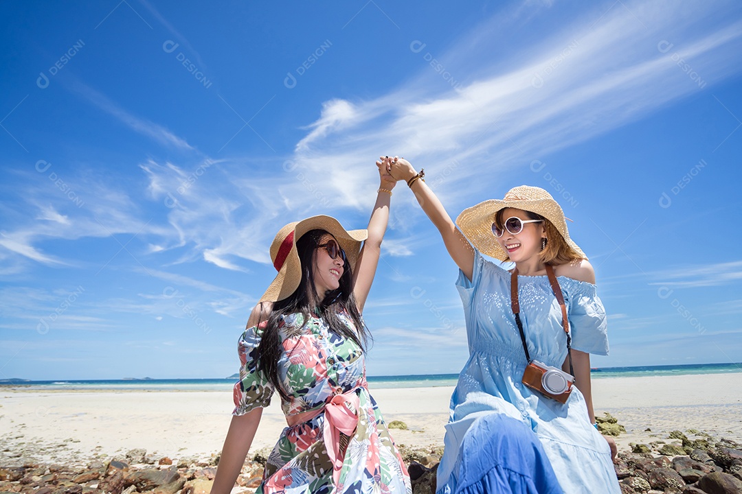 Jovens de vestido e chapéu na praia em tempo de férias