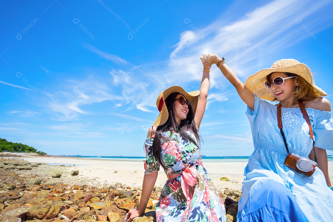 Jovens de vestido e chapéu na praia em tempo de férias