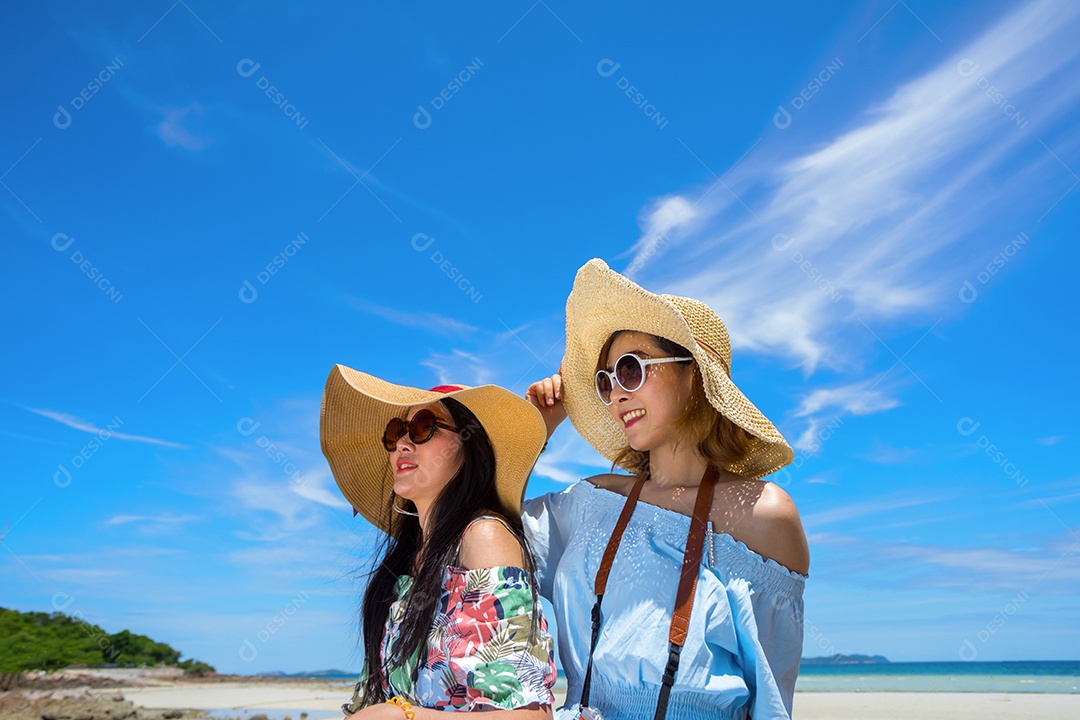 Jovens de vestido e chapéu na praia  em tempo de férias