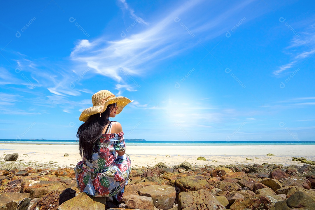 Jovem de vestido e chapéu na praia em tempo de férias