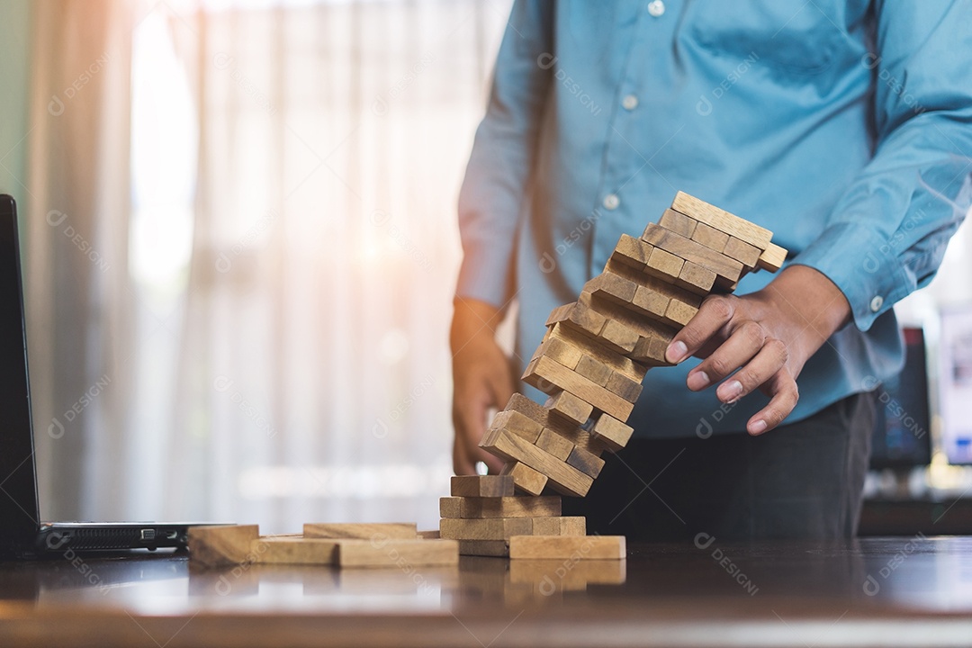 A mão do empresário que puxa o bloco de madeira