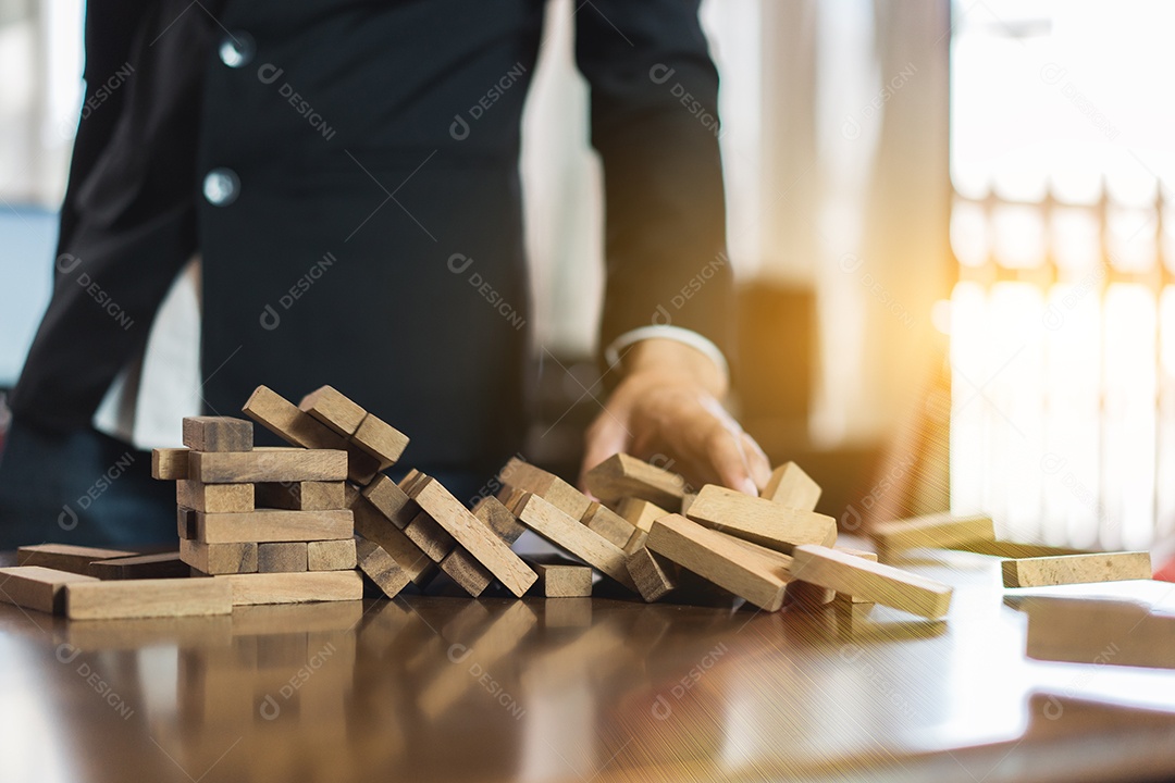 A mão do empresário que puxa o bloco de madeira