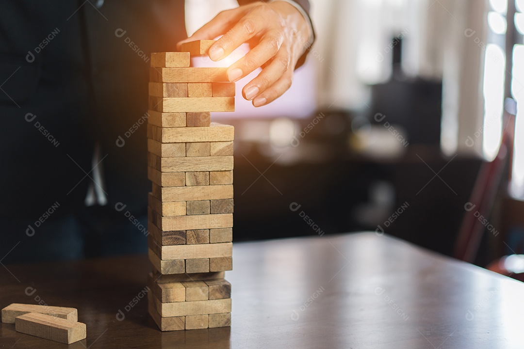 A mão do empresário que puxa o bloco de madeira