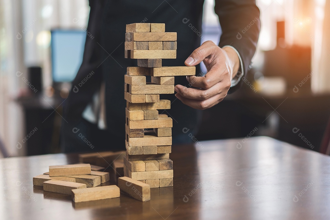 A mão do empresário que puxa o bloco de madeira