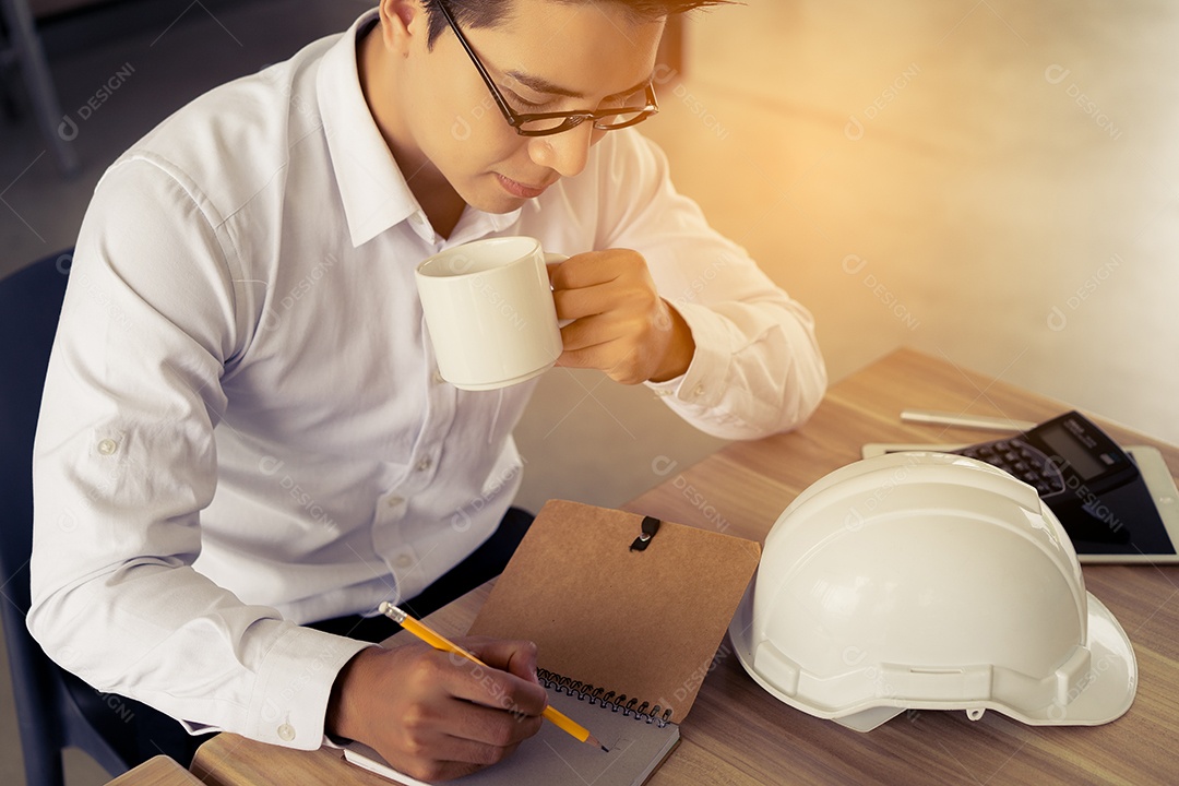 Engenheiro trabalhando na mesa de escritório com planta, plano de papel, documento