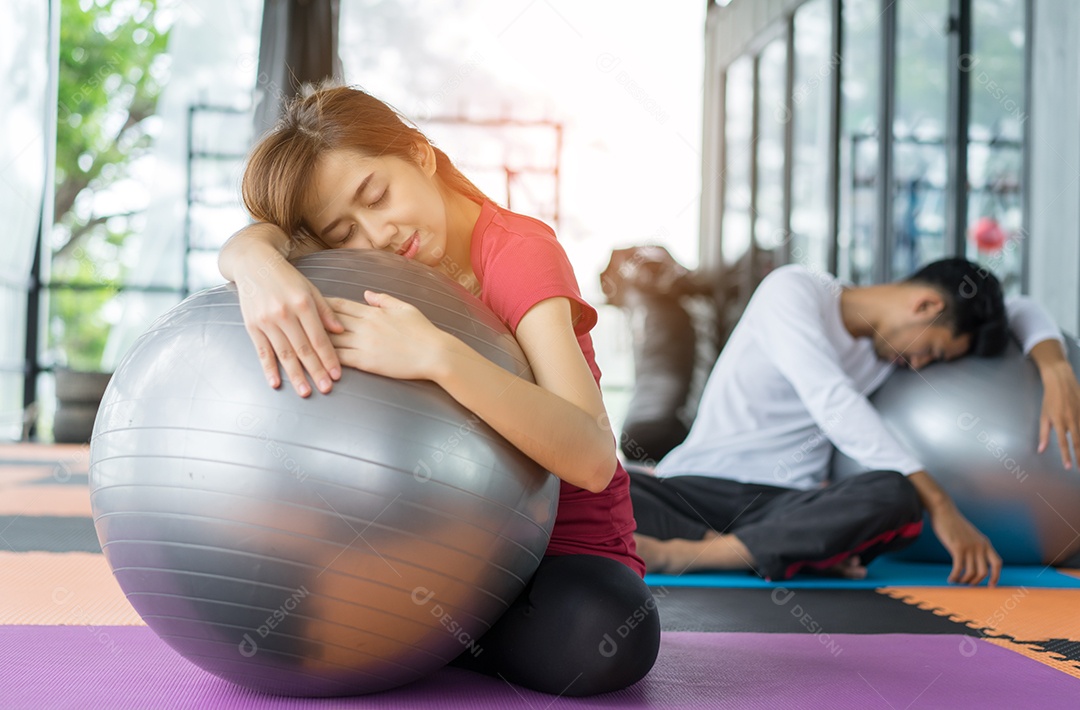 Jovem mulher asiática e homem fitness aeróbica com bola de ioga