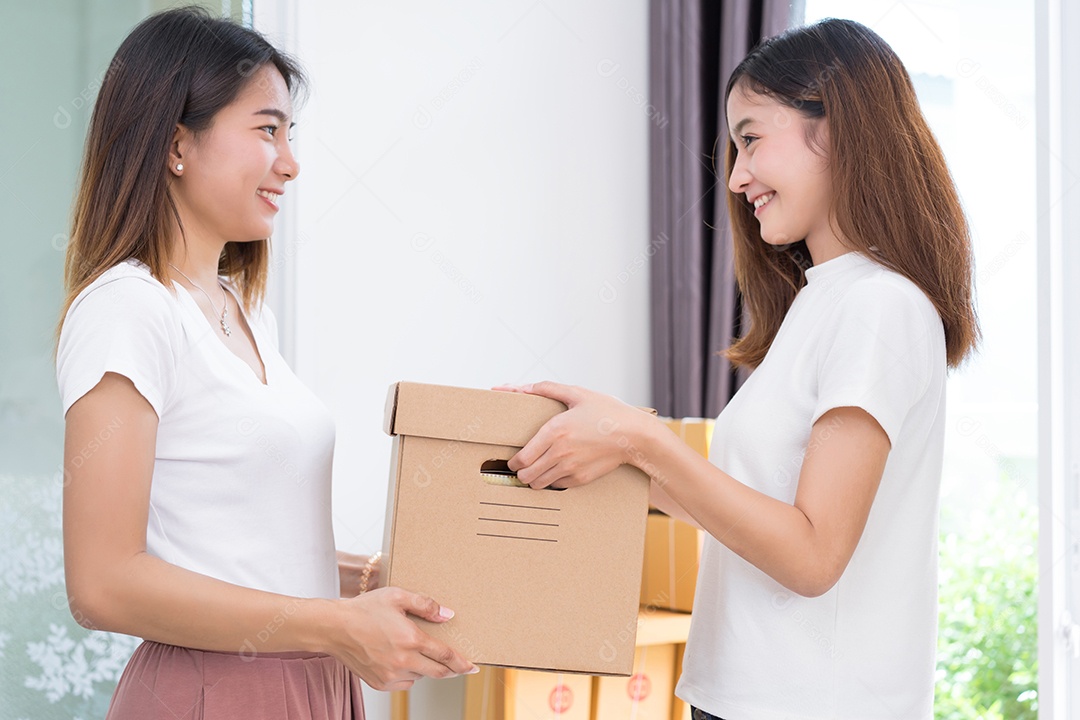 Jovem asiática juntos negócios freelancer privados trabalhando no escritório doméstico segurando a caixa de embalagem