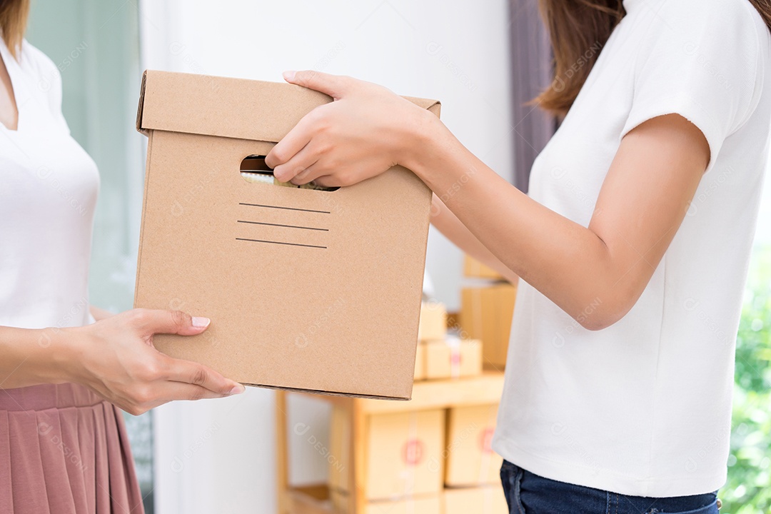 Jovem asiática juntos negócios freelancer privados trabalhando no escritório doméstico segurando a caixa de embalagem