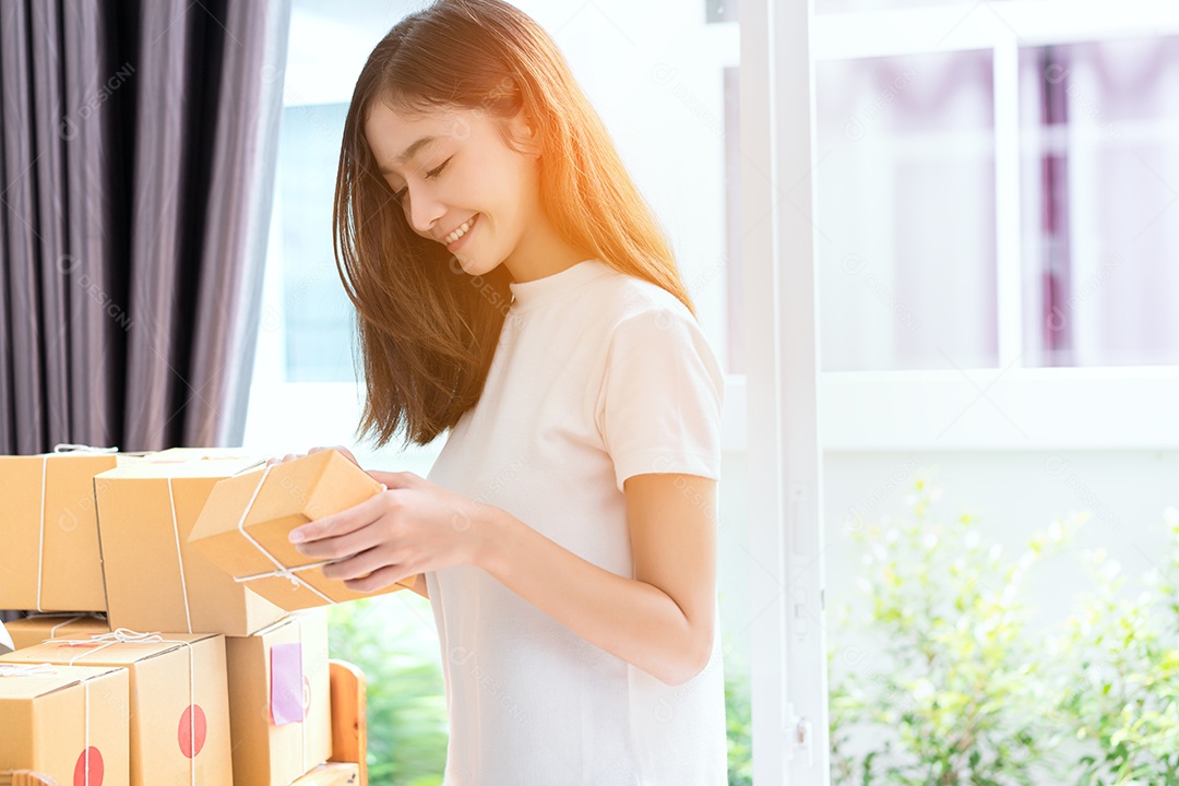 Jovem asiática freelancer de negócios entrega de caixa de produtos para clientes