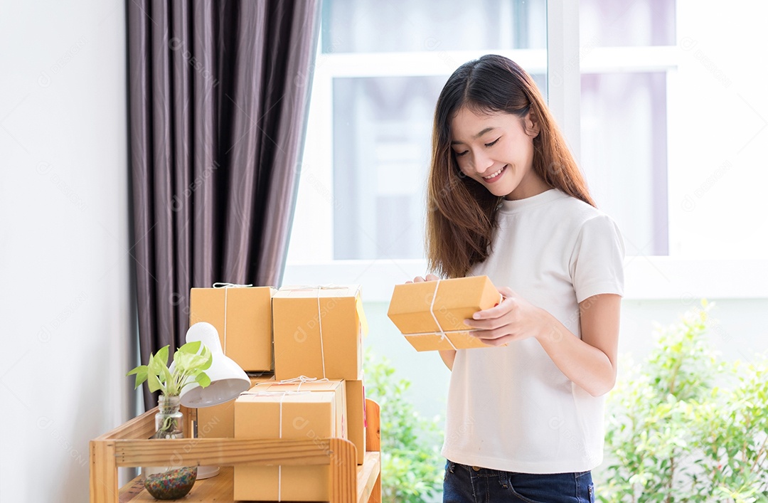 Jovem asiática freelancer de negócios entrega de caixa de produtos para clientes