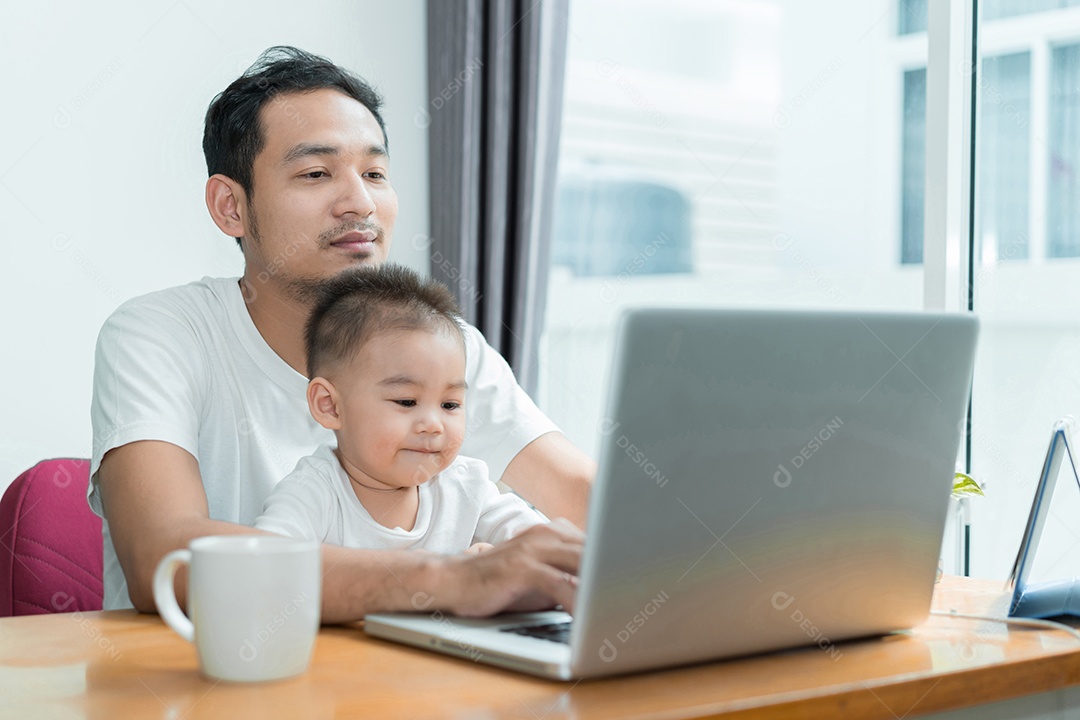 Pai asiático e filho pequeno digitando algo no computador portátil