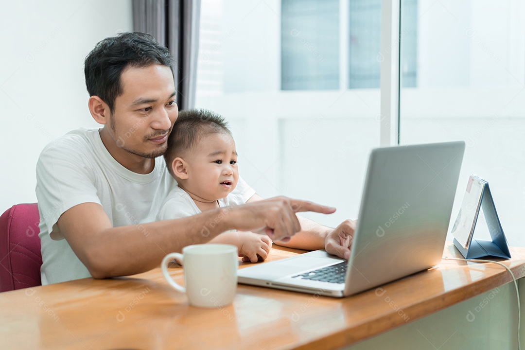 Pai asiático e filho pequeno digitando algo no computador portátil