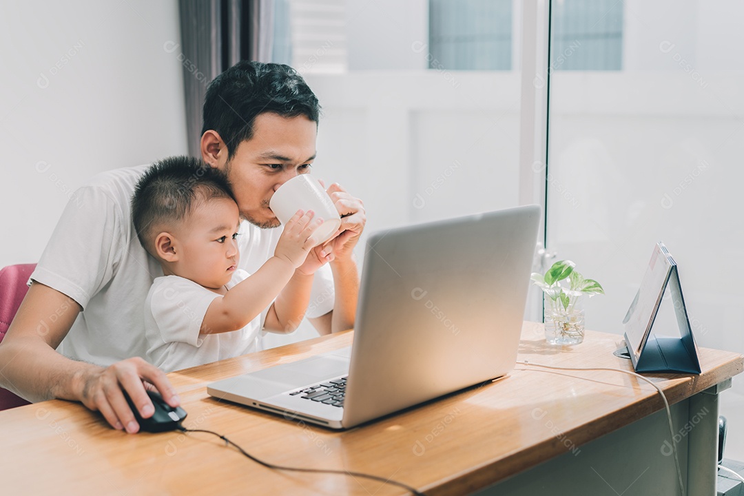 Pai asiático e filho pequeno digitando algo no computador