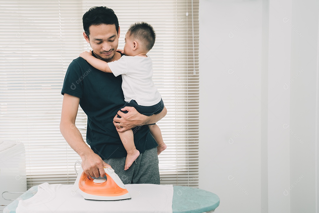 Conceito de família feliz, o pai pega o filho pequeno para passar roupas na tábua de passar