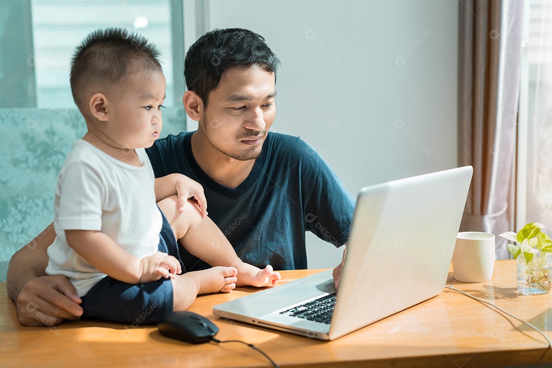 Pai asiático e filho pequeno assistindo algo no laptop