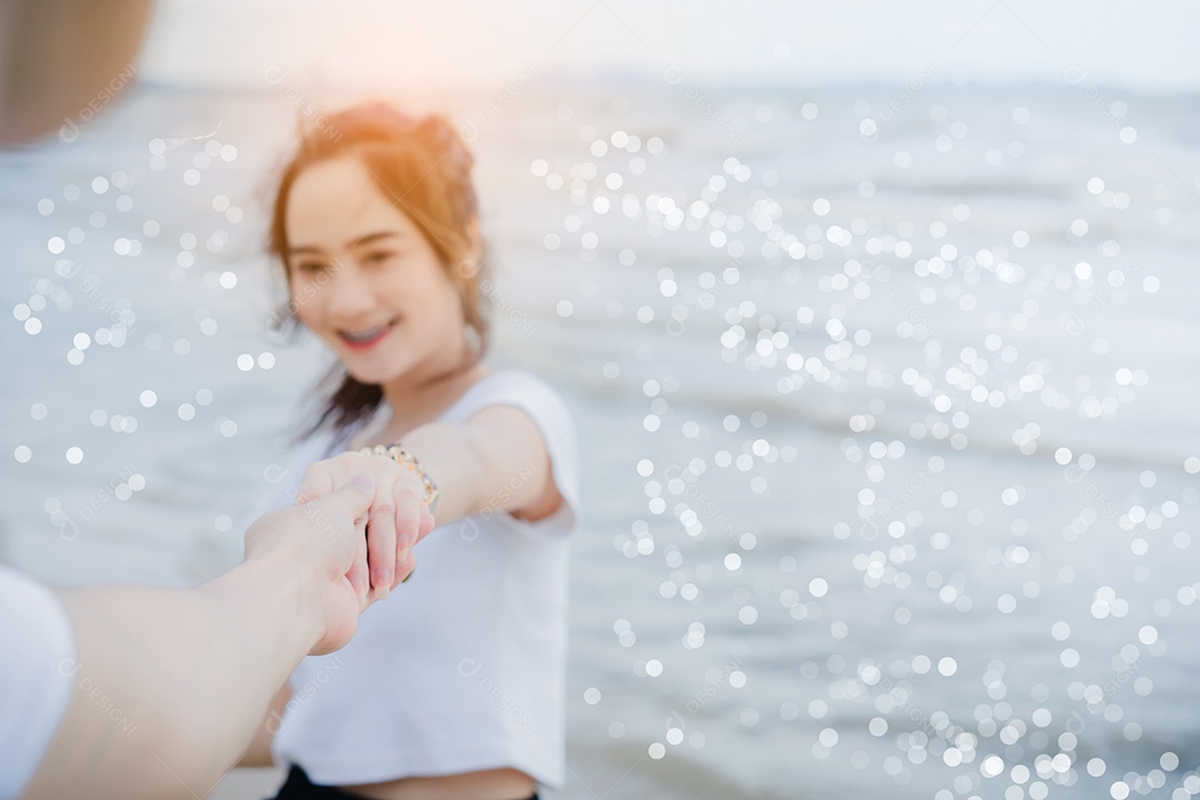 Jovem de mãos dadas com garota na praia e casal tendo felicidade