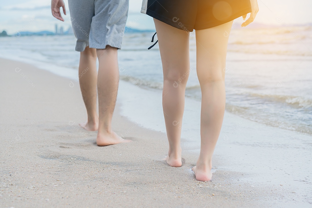 Homem e menina caminhando nas férias pôr do sol à beira-mar na praia