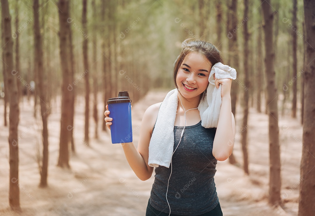 Linda mulher asiática bebendo garrafa de nutrição de shake de proteína na natureza da floresta