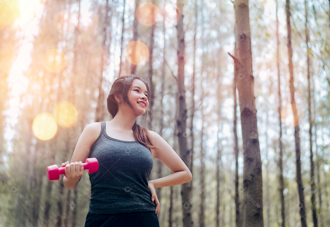 Linda mulher asiática com treino de halteres na natureza da floresta