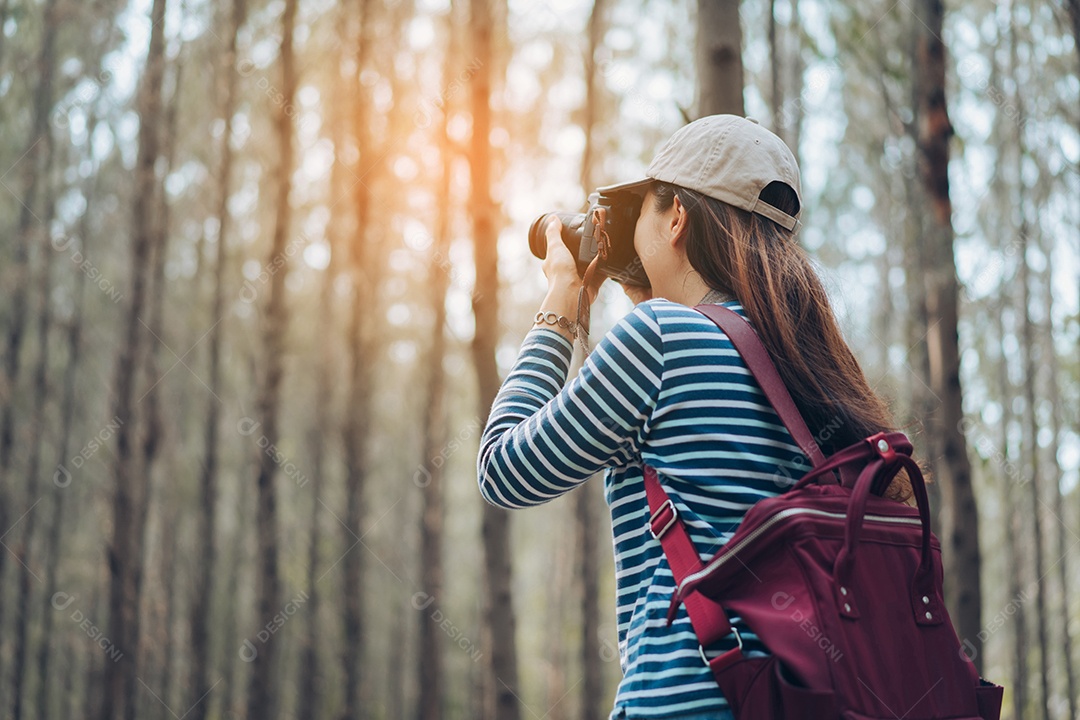 Mulher tirando foto na floresta com mochila