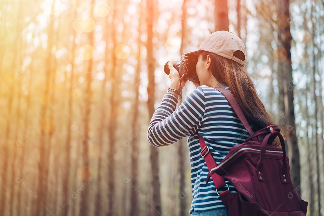 Mulher tirando foto na floresta com mochila