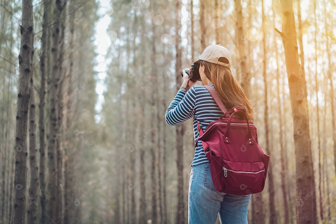Mulher tirando foto na floresta com mochila