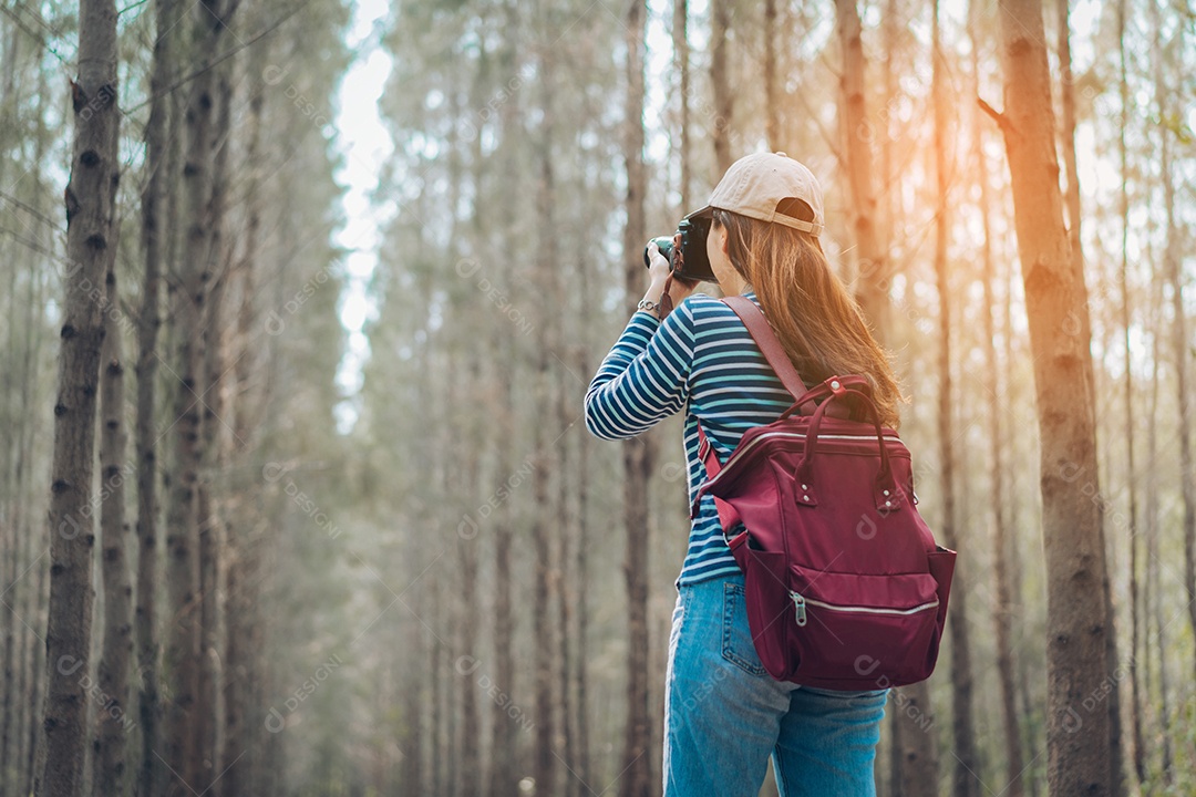 Mulher tirando foto na floresta com mochila