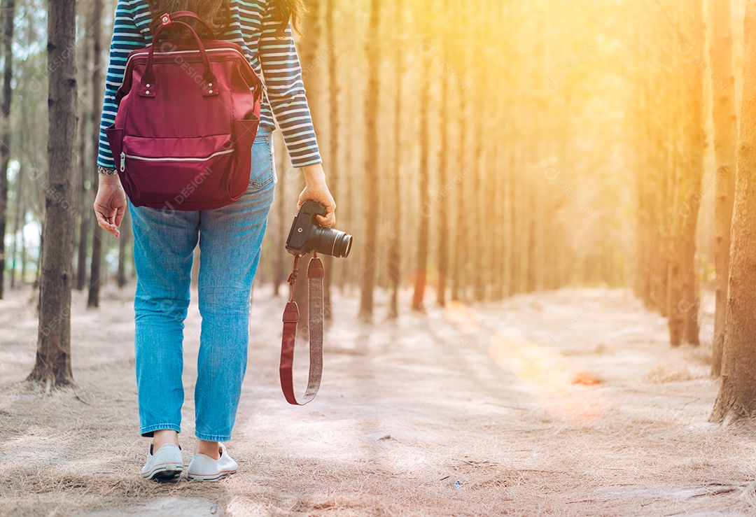Mulher andando na floresta com mochila para tirar uma foto
