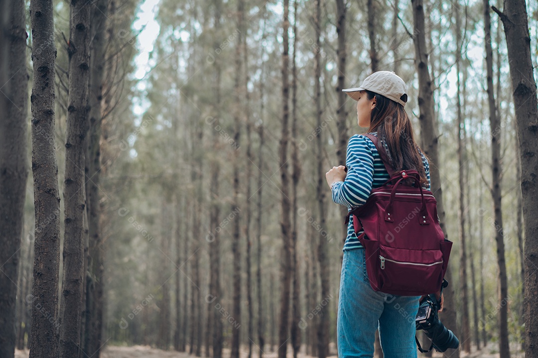 Mulher andando na floresta com mochila para tirar uma foto