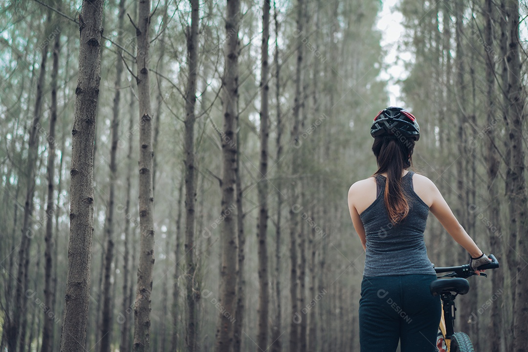 Mulher andando de bicicleta na floresta