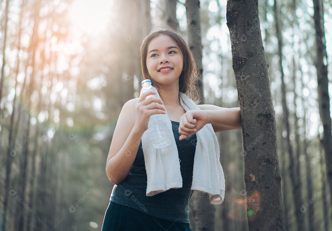 Garrafa de água potável de linda mulher asiática na natureza da floresta