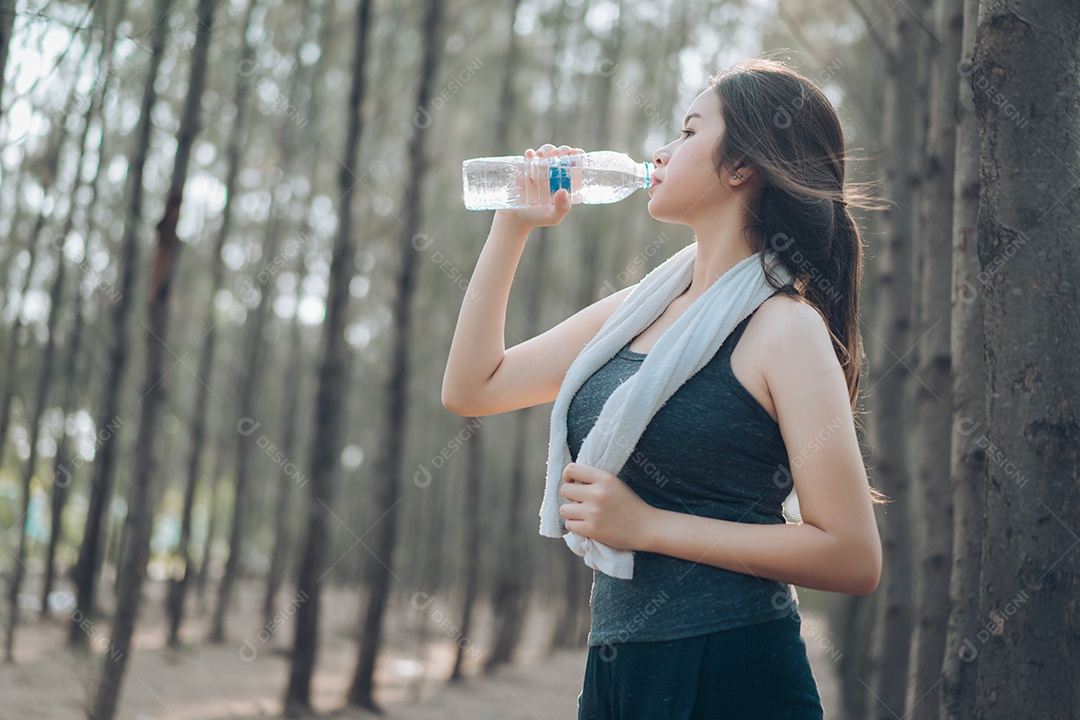 Garrafa de água potável de linda mulher asiática na natureza da floresta