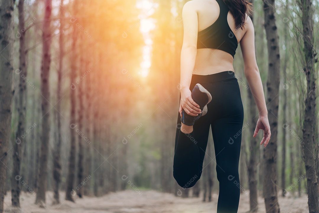 Jovem mulher se alongando para corrida na floresta