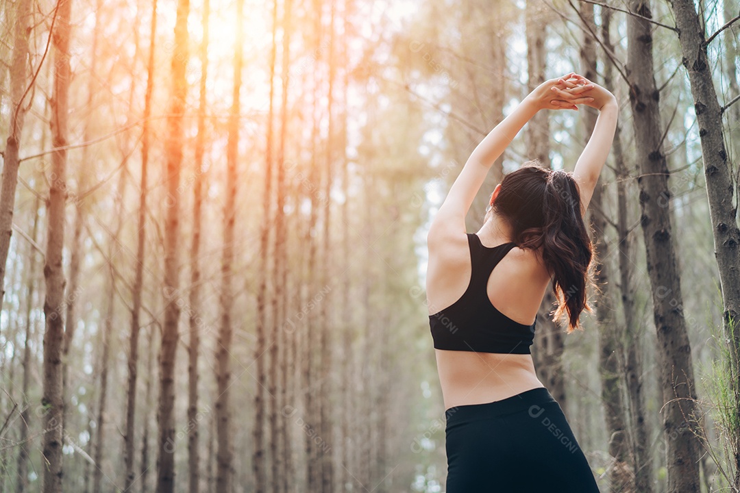 Jovem mulher se alongando para corrida na floresta