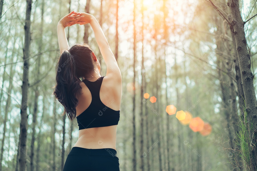 Jovem mulher se alongando para corrida na floresta