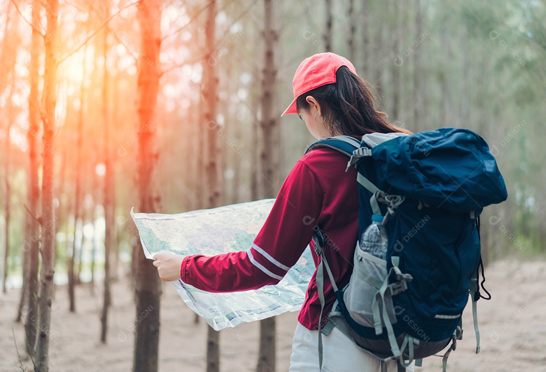 A mulher asiática viaja com a mochila na floresta