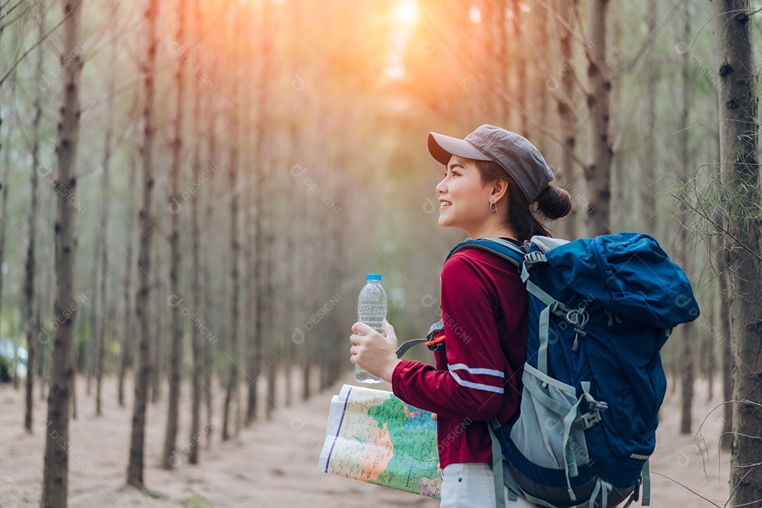 A mulher asiática viaja com a mochila na floresta