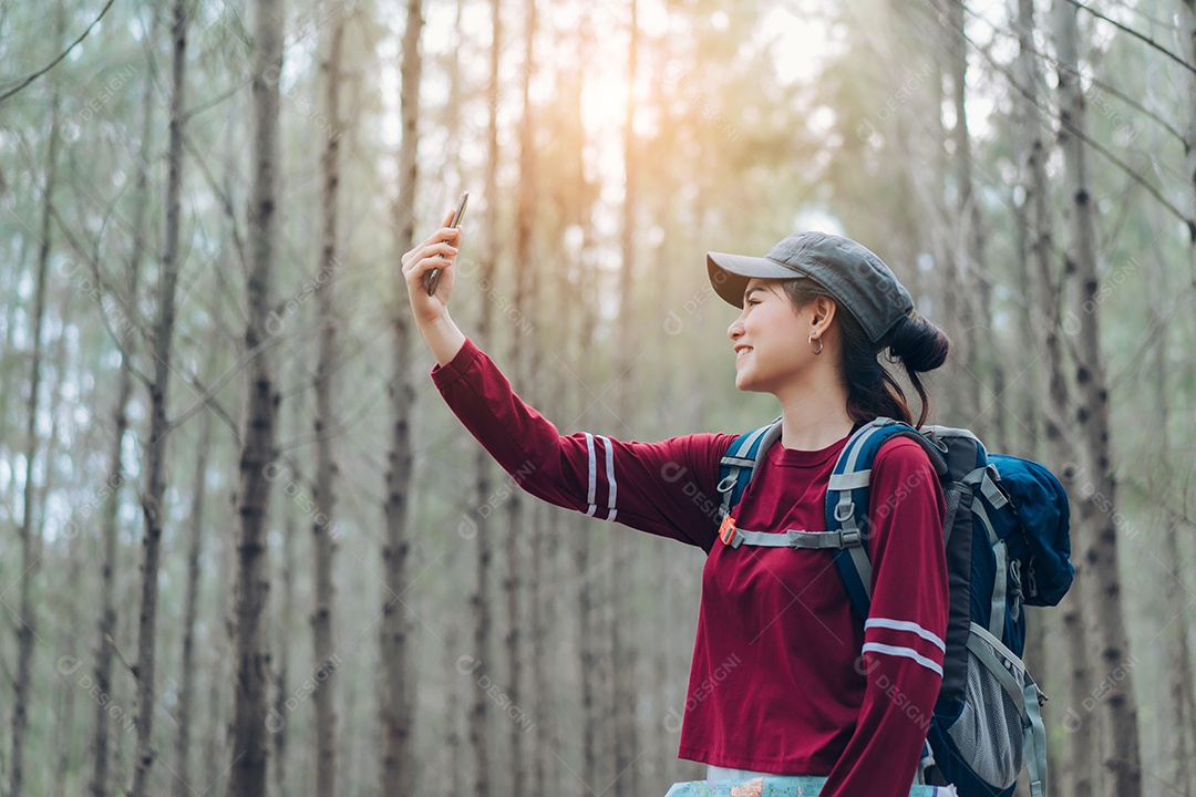 A mulher asiática viaja com a mochila na floresta