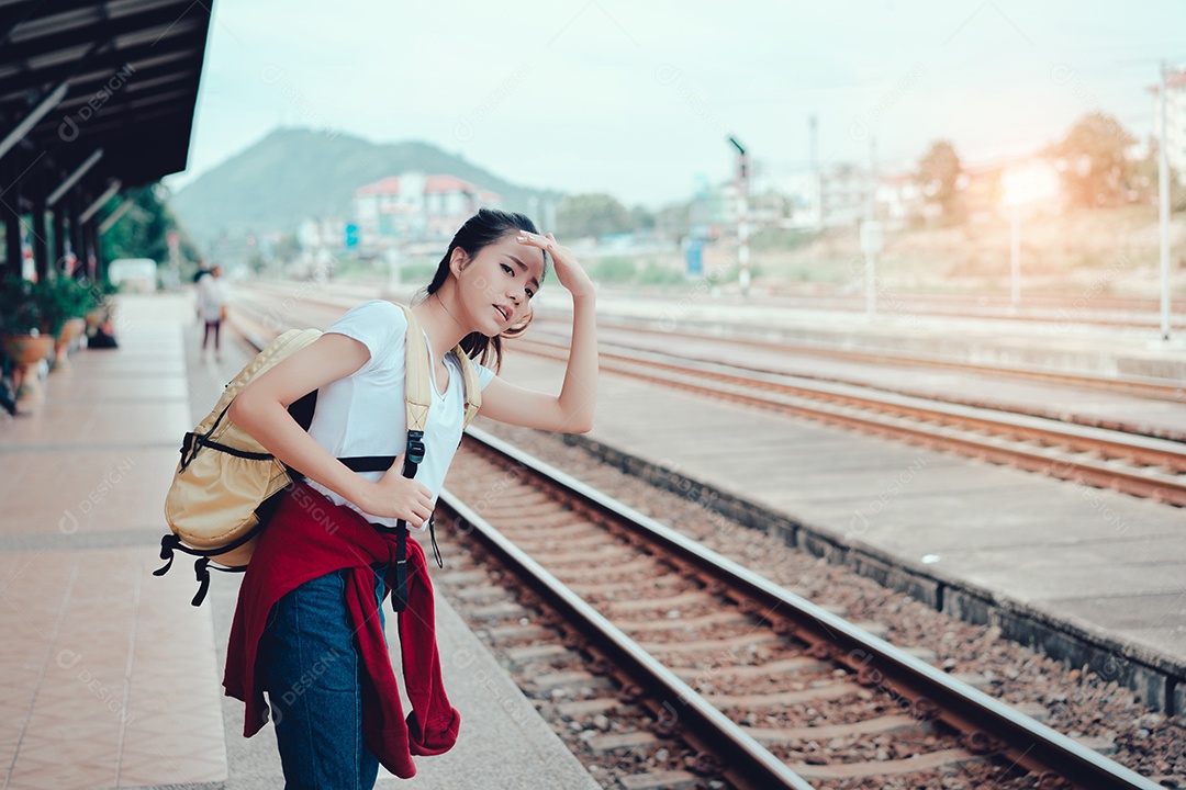 Jovem turista asiática em pé com a mochila esperando o trem