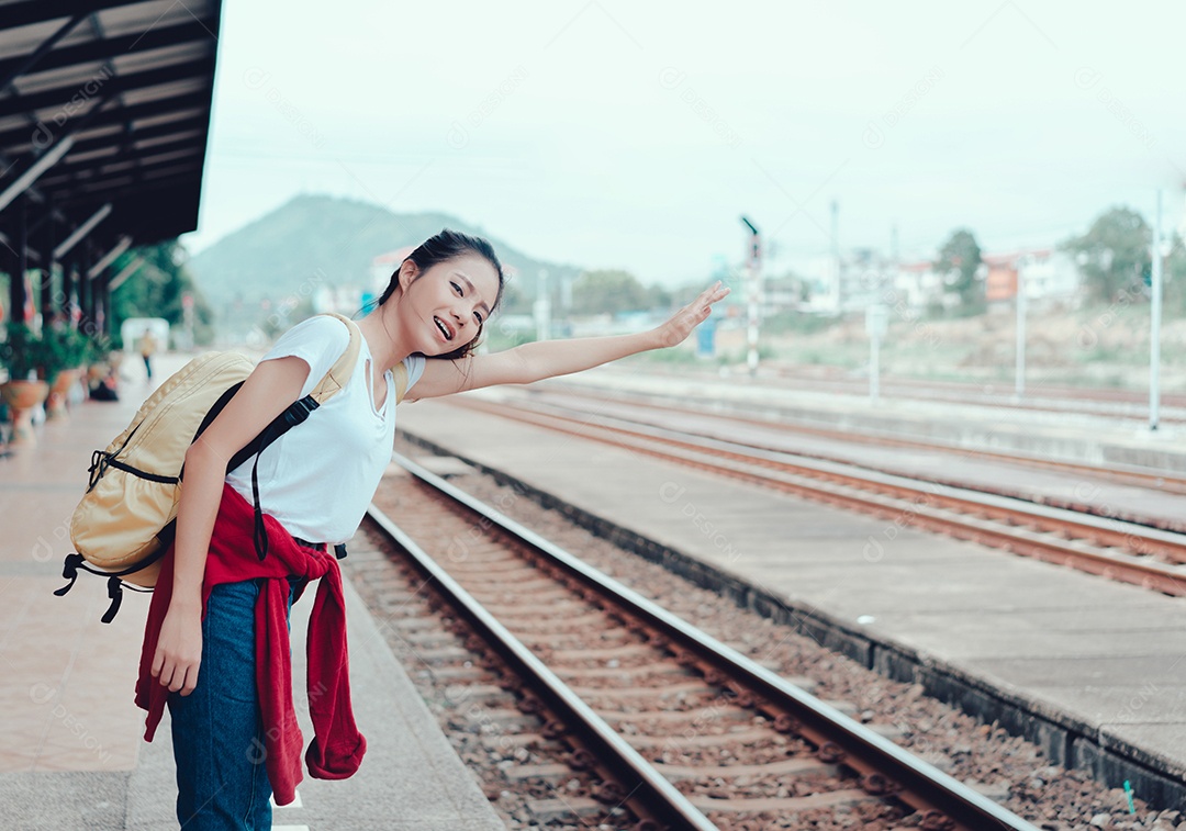 Jovem turista asiática em pé com a mochila esperando o trem