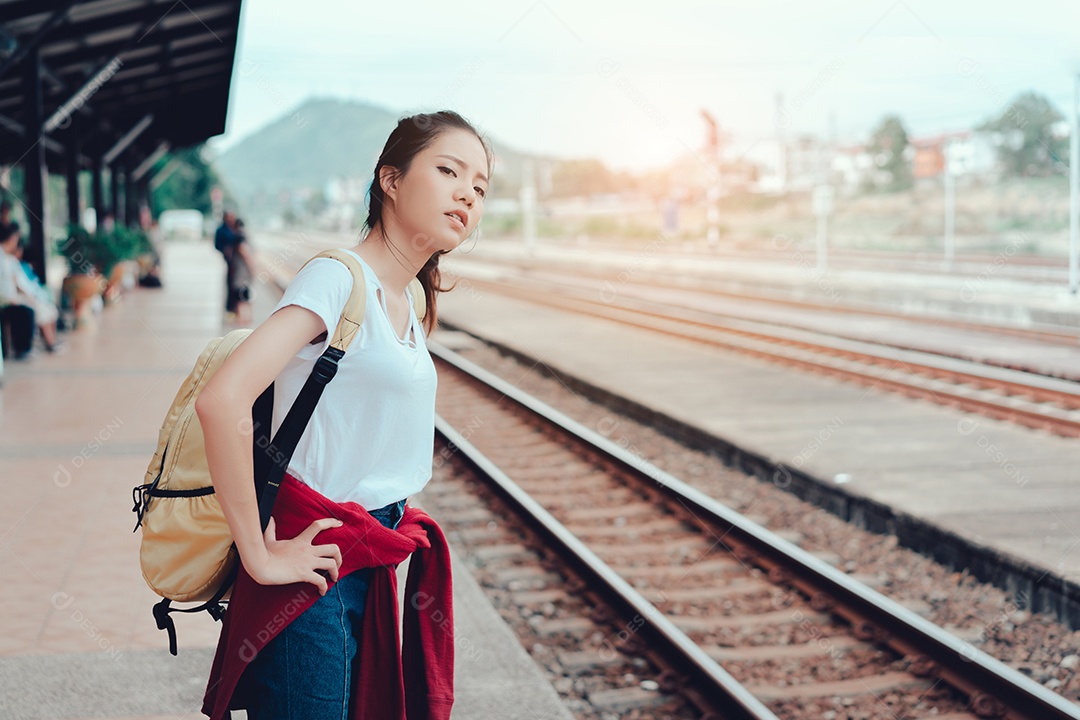 Jovem turista asiática em pé com a mochila esperando o trem