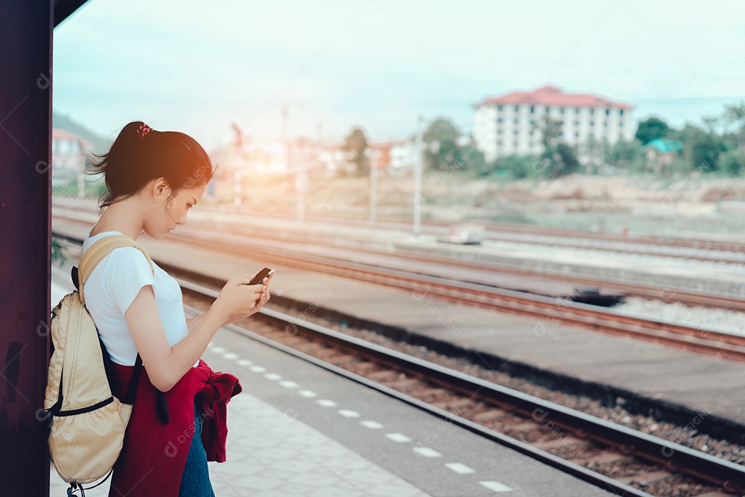 Jovem turista asiática em pé com a mochila esperando o trem