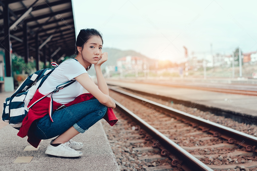 Uma jovem turista ambulante na ferrovia lateral segurando smartphone com mochila