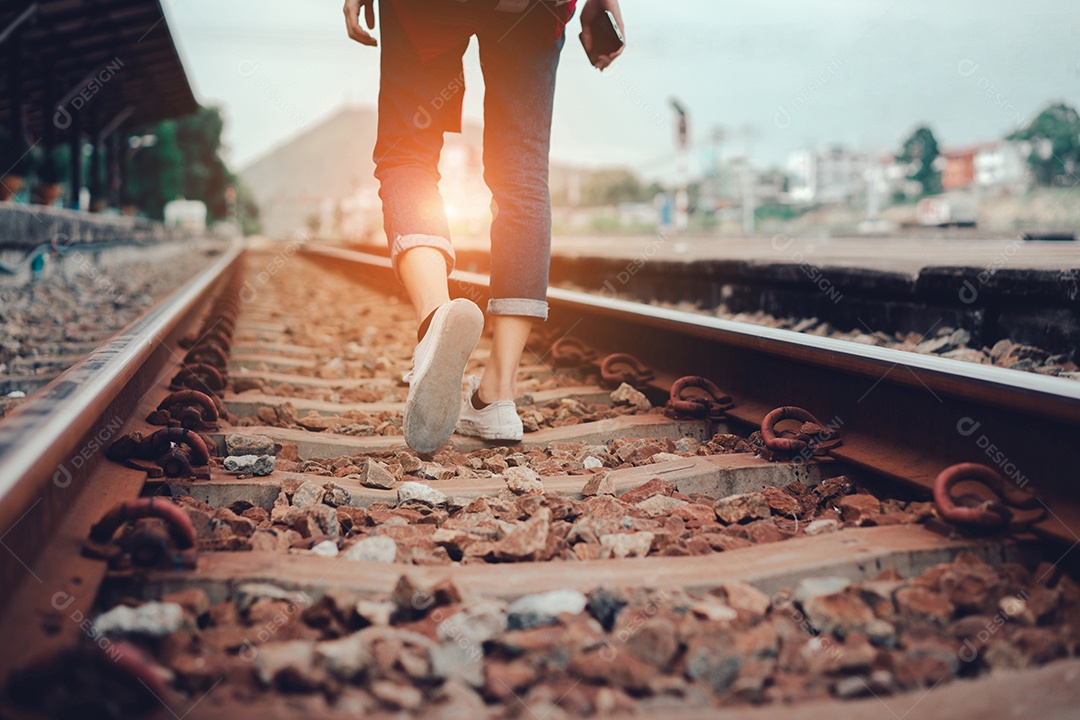 Uma jovem turista ambulante na ferrovia lateral segurando smartphone com mochila