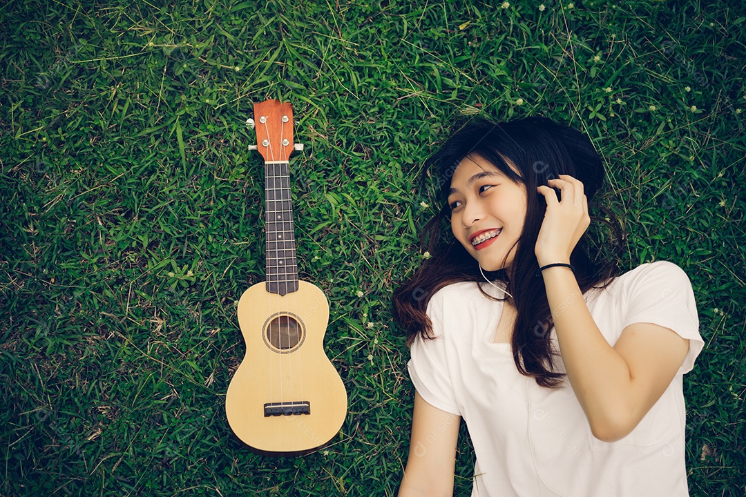 Jovem mulher tocando violão sentada no gramado