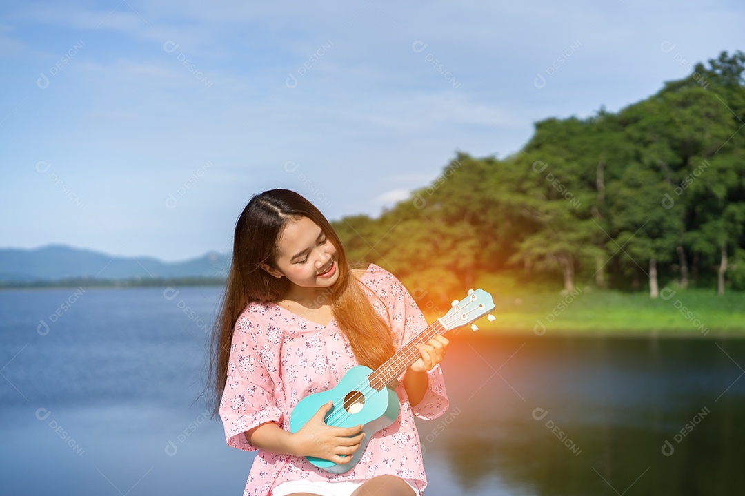 Mulher jovem segurando ukulele no lago